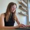 Portrait of Sarah Fossheim sitting working on a laptop.