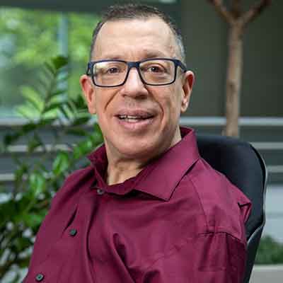 Portrait of Dave Dame, a man with short buzz cut hair and glasses.